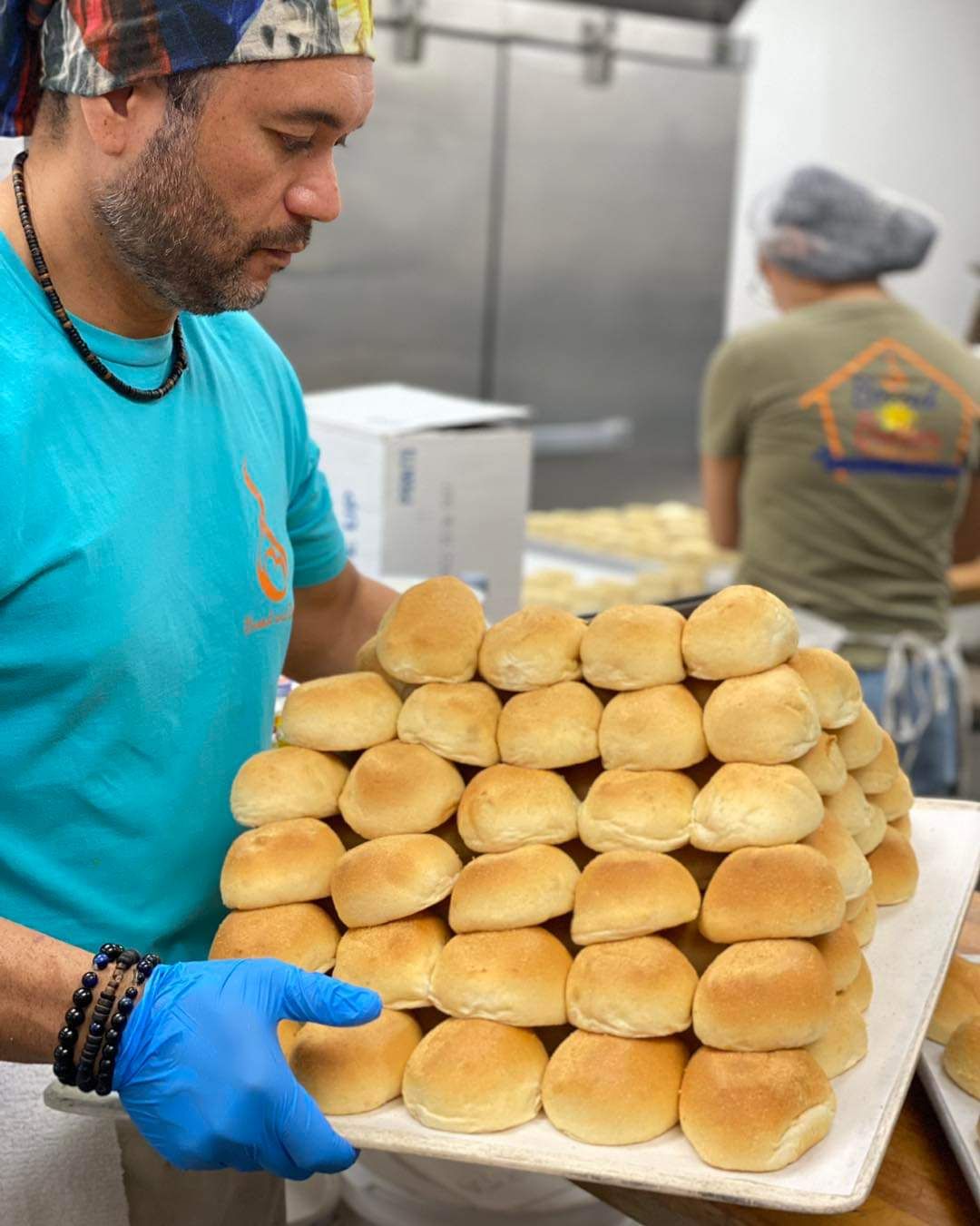 A baker holding a fresh tray of rolls at Bread and Butter